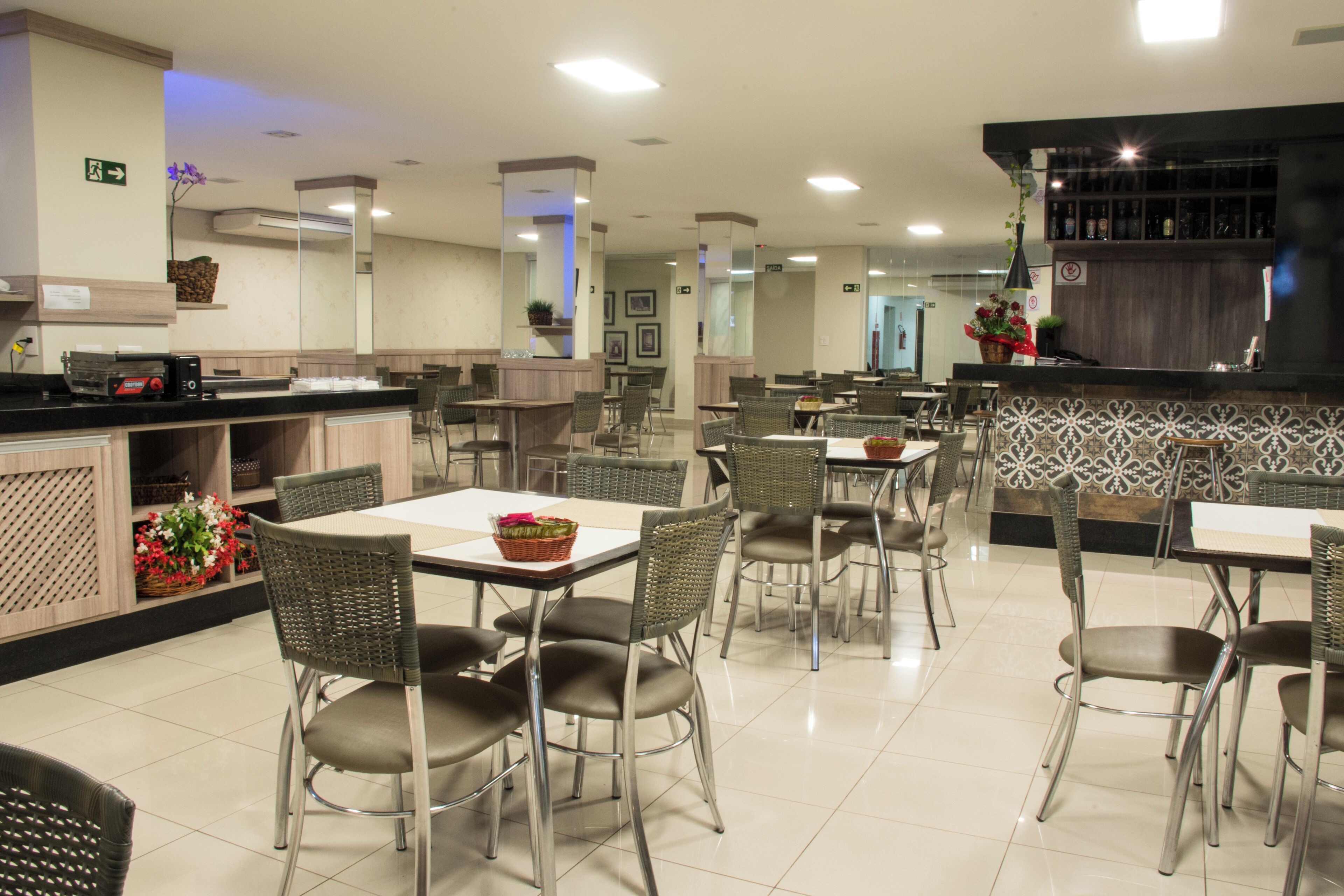 Un restaurante espacioso con varias mesas y sillas, una zona de bar y una barra con espejo.