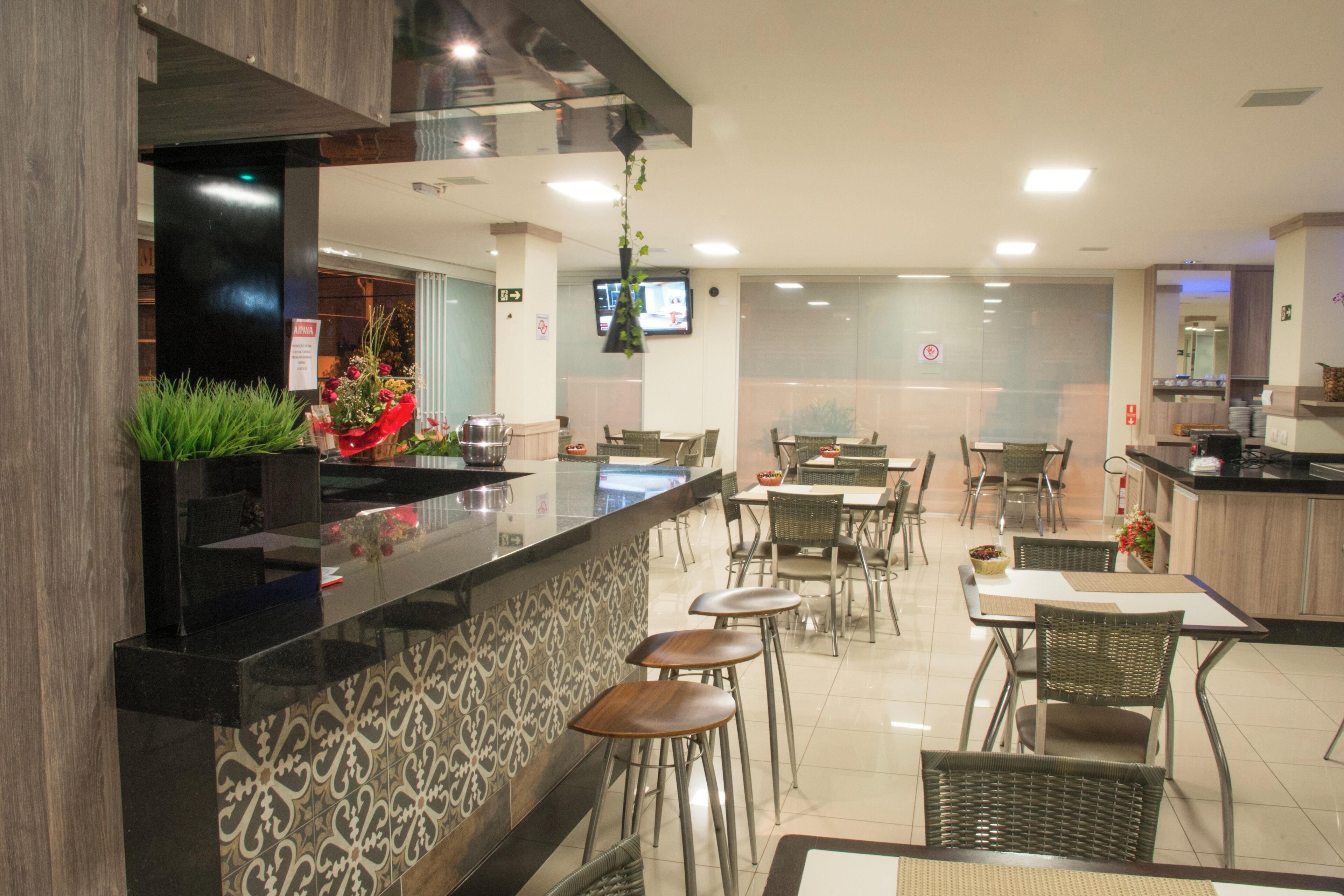 Un ristorante moderno con un bancone nero, piastrelle decorate e sedie in vimini.