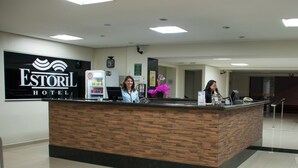 Una recepción de hotel con un diseño moderno, un reloj y un cartel del Hotel Estoril.