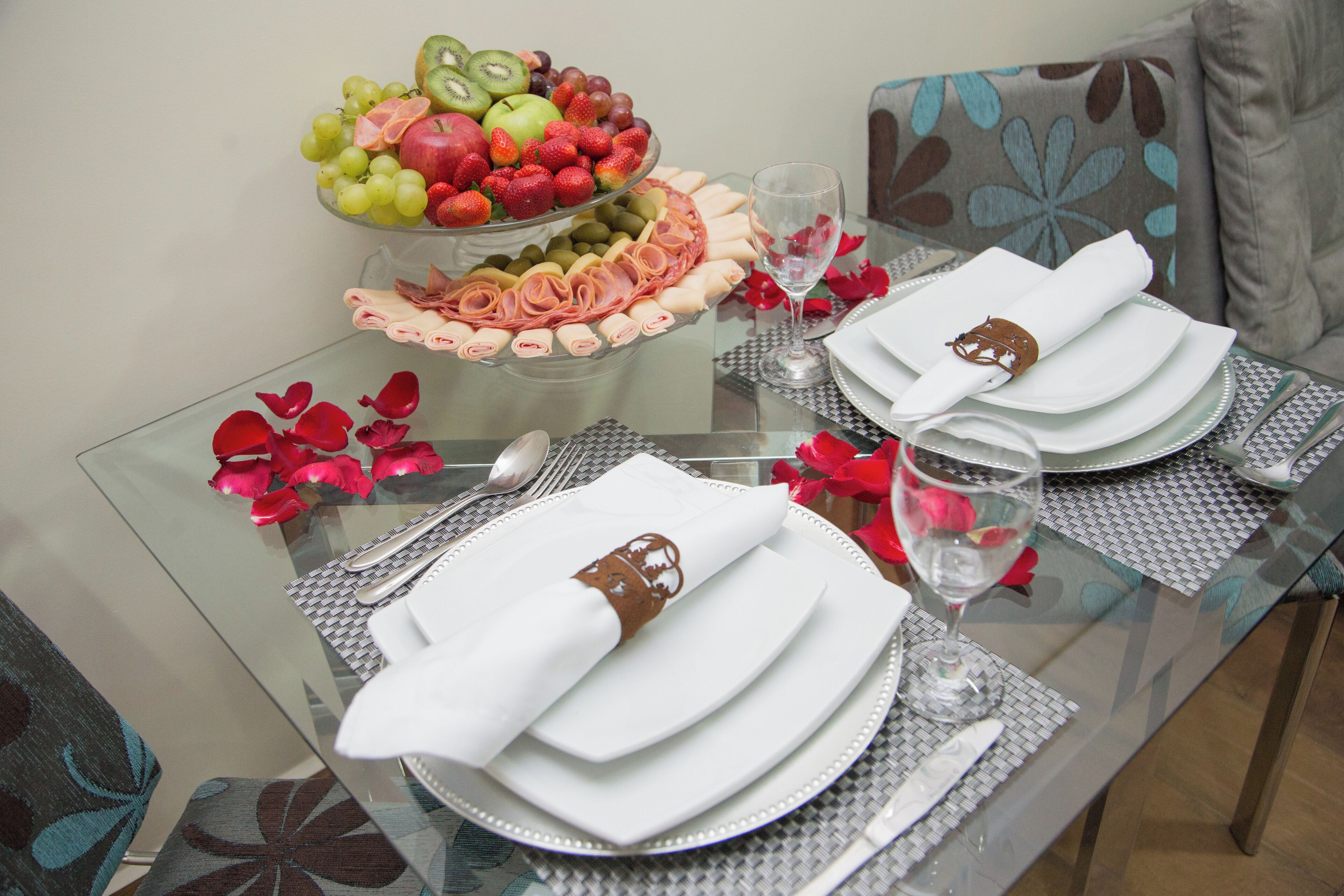 A dining table set with plates, cutlery, and a fruit platter.