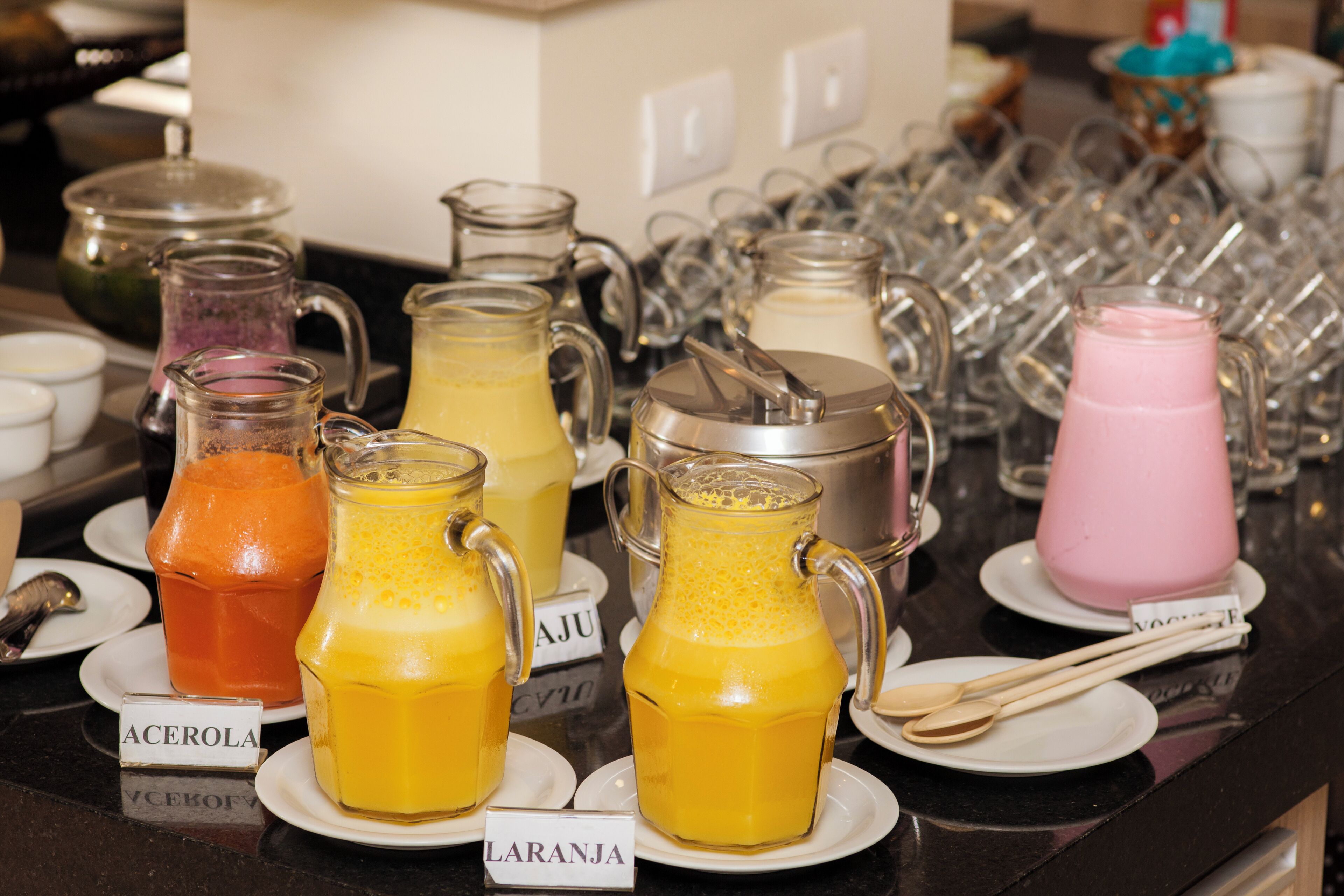 A breakfast buffet with various fruit juices and a coffee station.