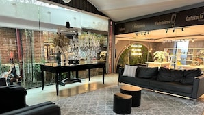 A modern interior with a glass wall, a black sofa, a coffee table, and a patterned rug. - Villa Verde Hotel (Avare)