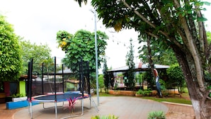 A trampoline in a garden area with potted plants and a covered seating area. - Villa Verde Hotel (Avare)