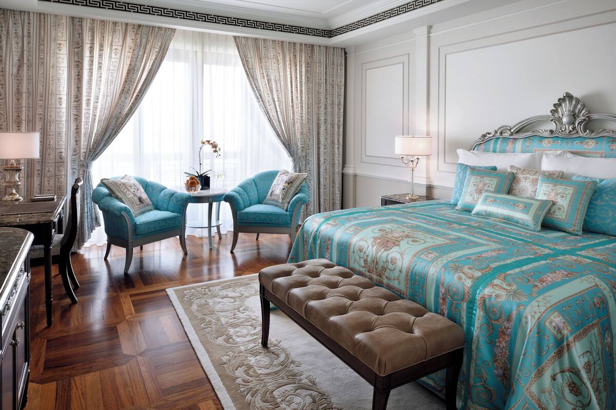 Ein Schlafzimmer mit einem großen Bett, zwei Sesseln, einem kleinen Tisch und einer Bank.