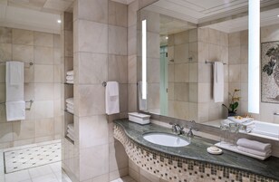 A bathroom with a large mirror, a sink, and a shower area.