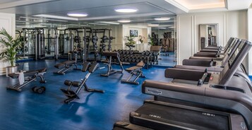 A gym with various exercise equipment, including treadmills, dumbbells, and weight machines.