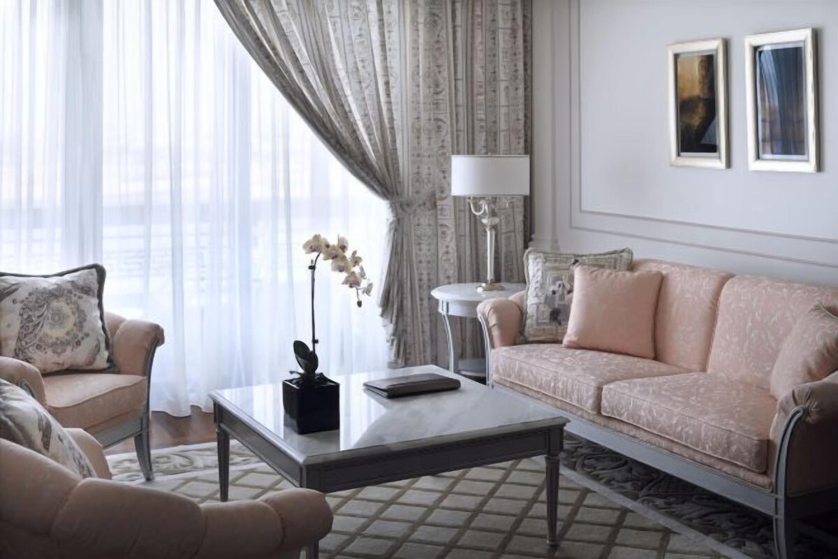 Un salon avec un canapé, des fauteuils, une table basse, une lampe et un vase de fleurs.
