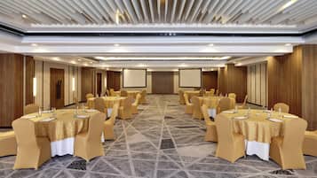 A conference room with multiple tables, chairs, and a large screen.