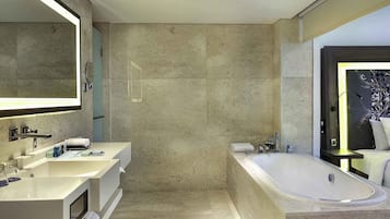 Un baño moderno con un espejo grande, dos lavamanos, una bañera y una ducha.