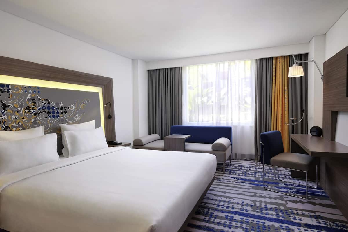 Habitación de hotel con una cama grande, un escritorio, una silla y un sofá.