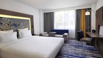 Habitación de hotel con una cama grande, un escritorio, una silla y un sofá.