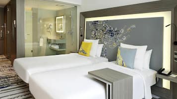 Une chambre d’hôtel avec deux lits, une salle de bain dotée d’une douche en verre et un mur décoratif.