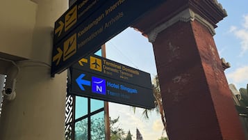 Skilte der viser vej til internationale og indenlandske ankomster, samt et skilt for Hotel Singgah Transit Hotel.