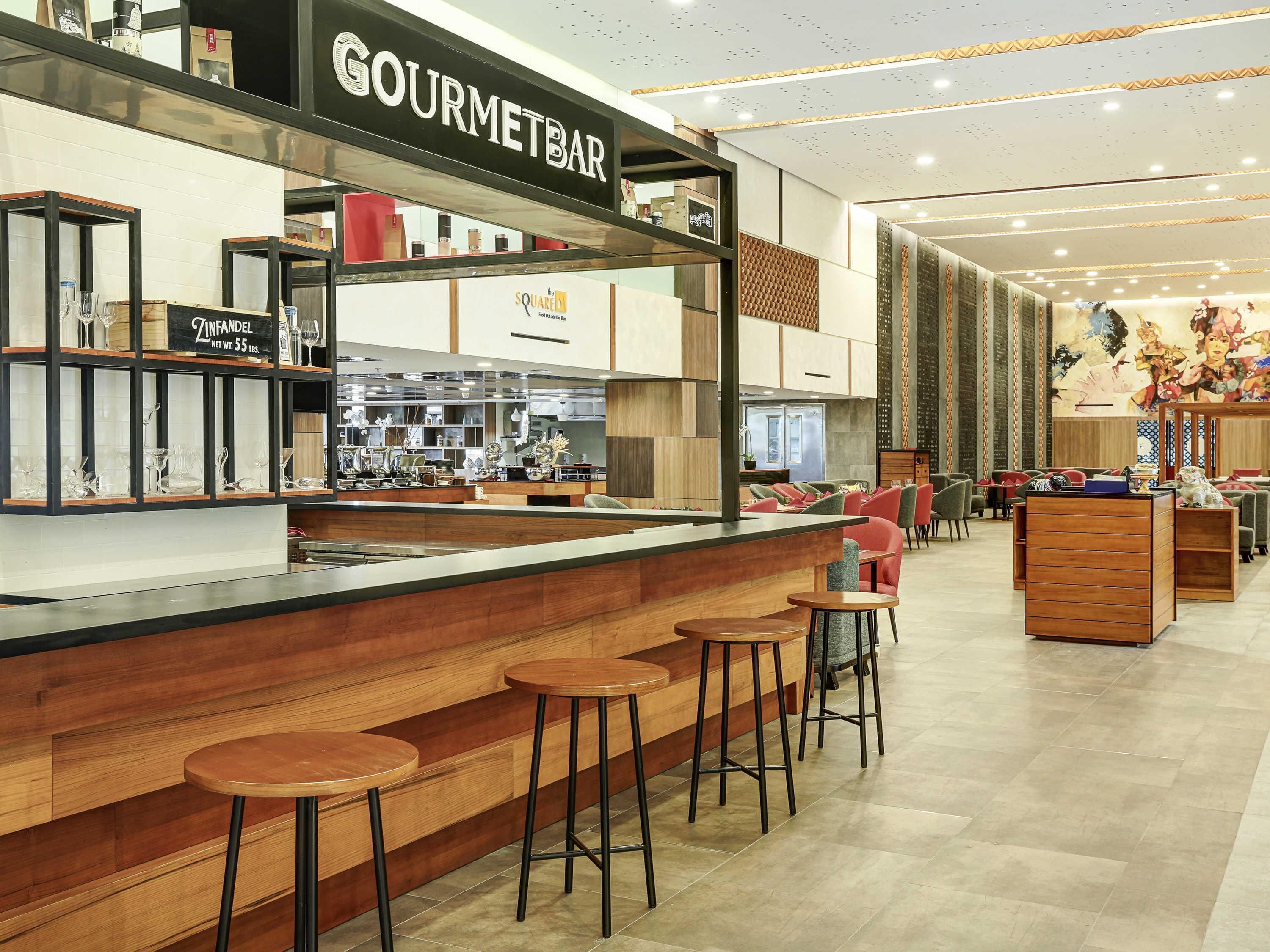 A modern bar area with a counter, stools, and a sign reading 'GOURMETBAR'.