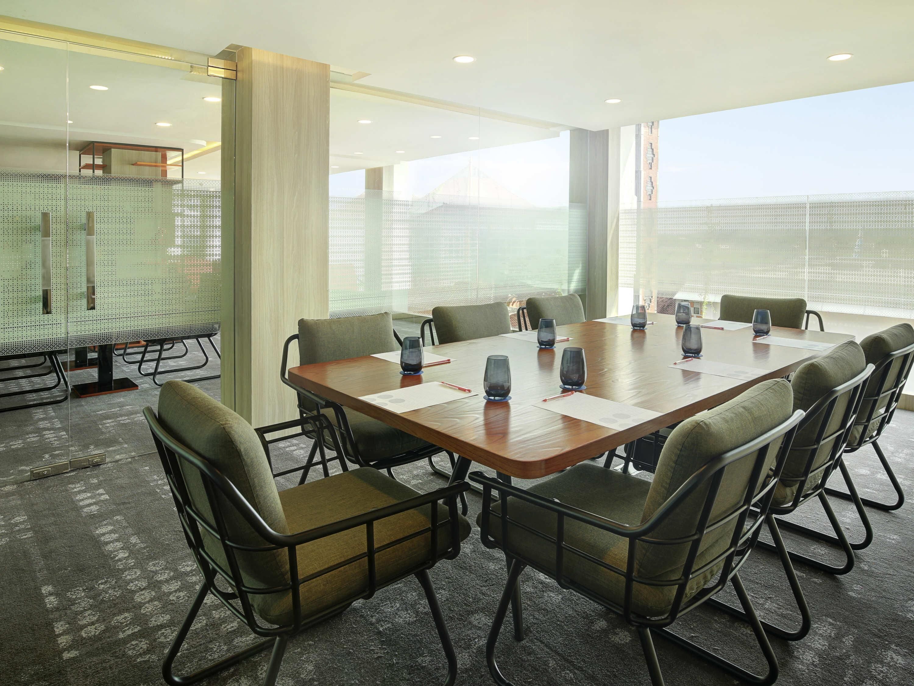 A conference room with a large table, chairs, and glass partitions.