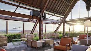 An outdoor seating area with wicker furniture and a view of the airport. - Novotel Bali Ngurah Rai Airport (Tuban)