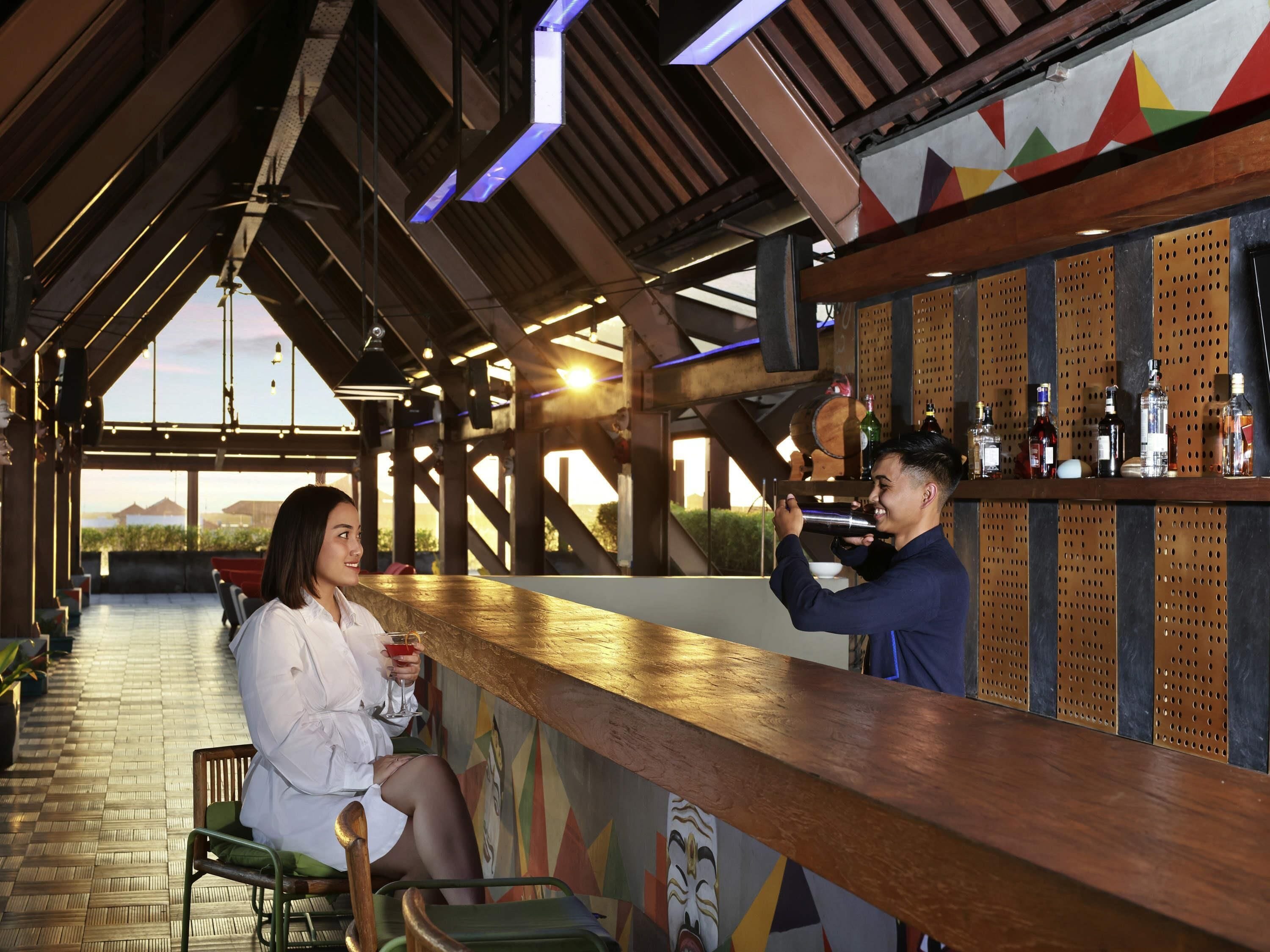 Zona de bar con mostrador de madera, asientos y vistas al exterior.