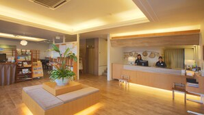 Un hall d’entrée spacieux avec un comptoir de réception, un espace salon et une grande plante en pot.