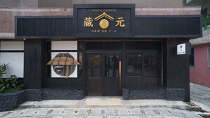 Un bâtiment sur lequel on peut lire une enseigne indiquant « SAKE & GALLERY » ainsi que des caractères japonais.