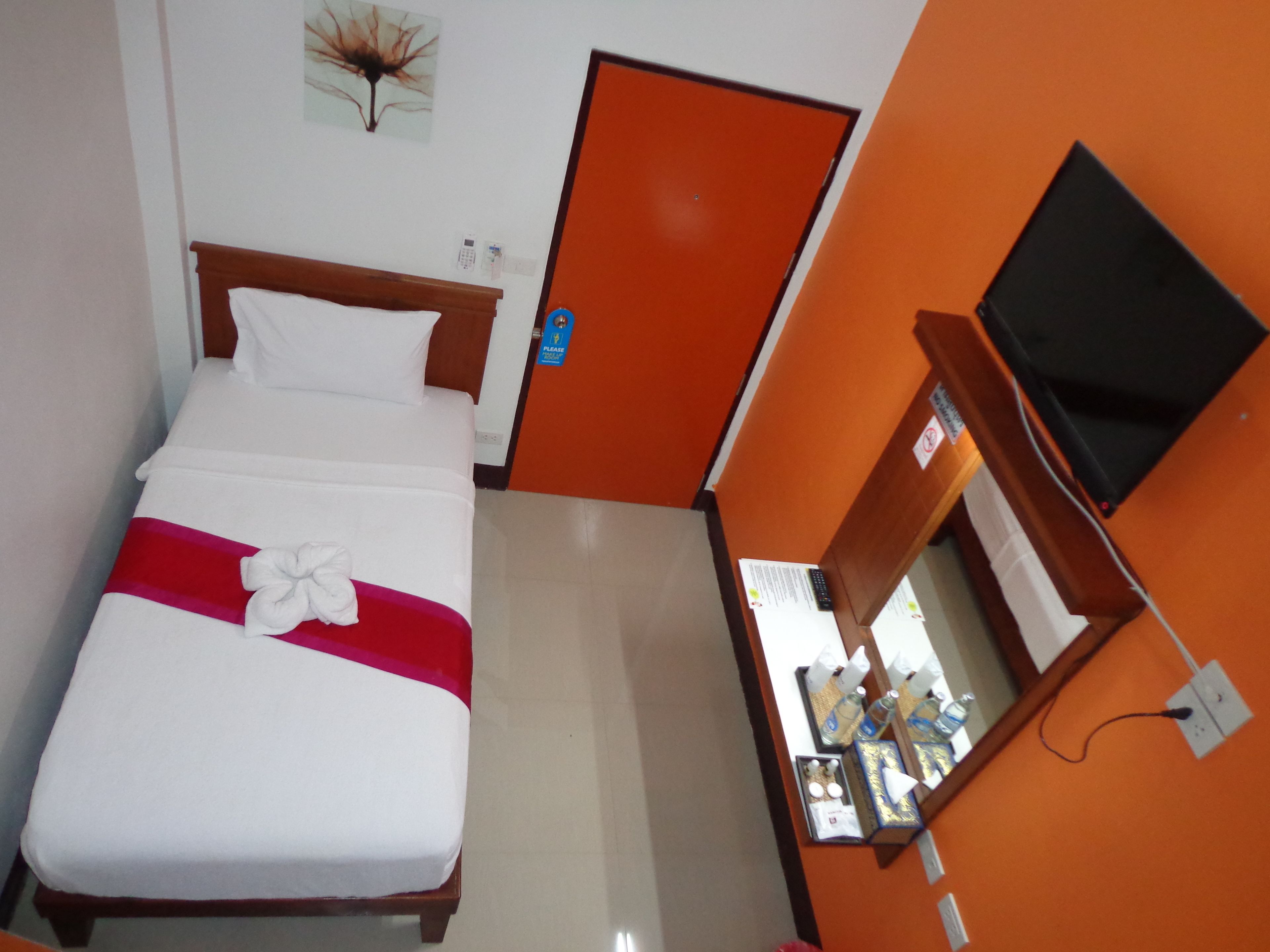 A hotel room with a bed, a television, a desk with a computer, and a door.