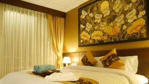 A hotel room with a large bed, white linens, a blue towel, and a painting of flowers on the wall. - Golden Moon Aonang (Krabi)