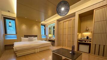 A modern hotel room with a large bed, a desk, and a walk-in closet.