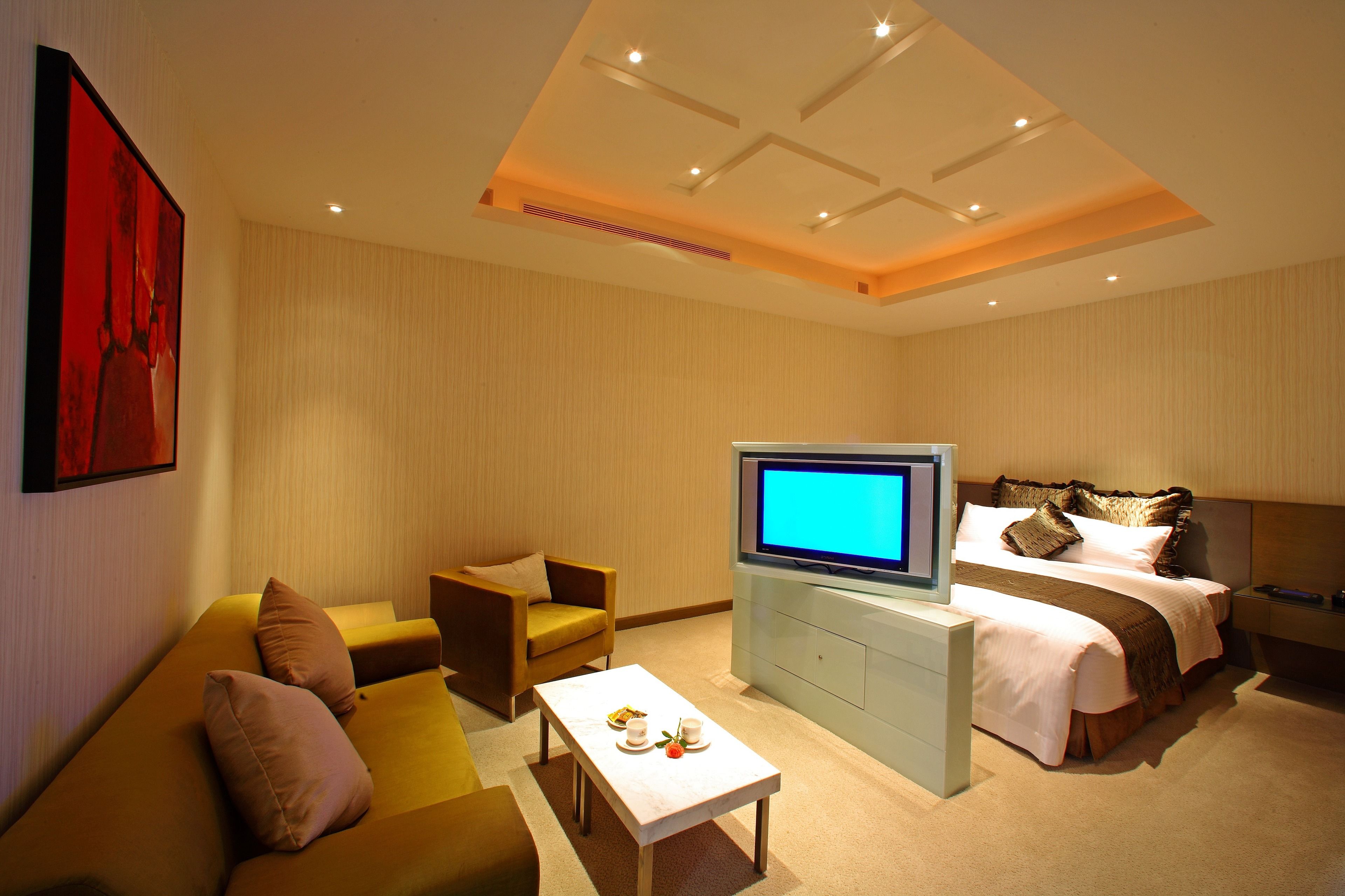 Een hotelkamer met een bank, een televisie, een bed en een salontafel.