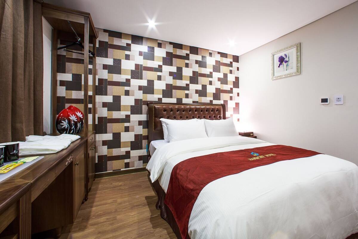 Una habitación de hotel con una cama, un escritorio, un armario y una pared con diseño geométrico.