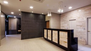 A modern reception area with a dark wall, light floor, and a black reception desk. - Harmony Hotel (Seoul)