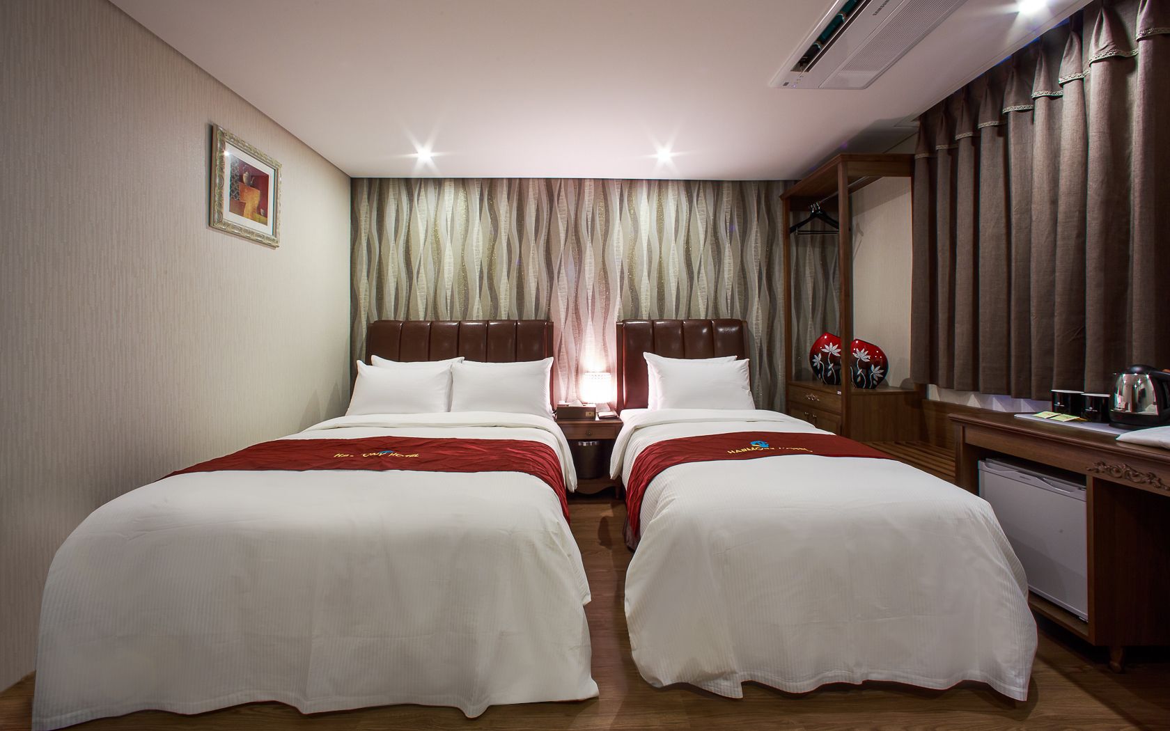 Habitación de hotel con dos camas, un escritorio, un espejo y un armario.