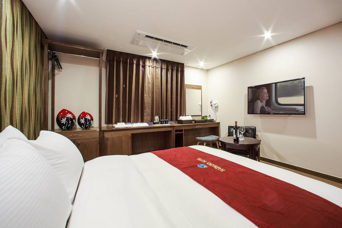 Una habitación de hotel con cama, escritorio, silla, televisión y minibar.