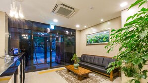 A modern lobby with a reception desk, a leather sofa, a coffee table, and a large window with a view of the street. - Harmony Hotel (Seoul)