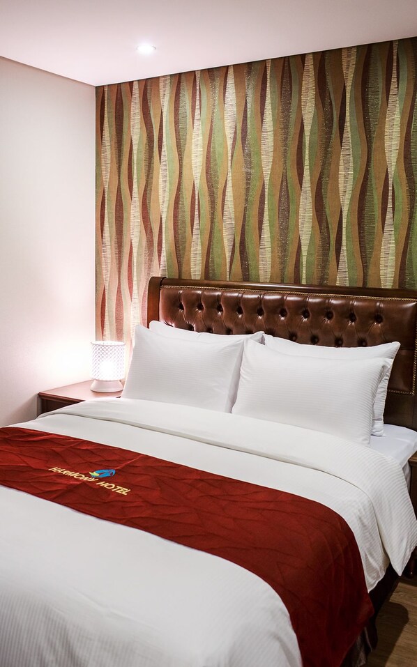 Une chambre d’hôtel avec un lit, une tête de lit et un mur décoré d’un motif.