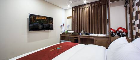 Une chambre d’hôtel équipée d’un lit, d’un bureau, d’un miroir et d’un téléviseur fixé au mur.