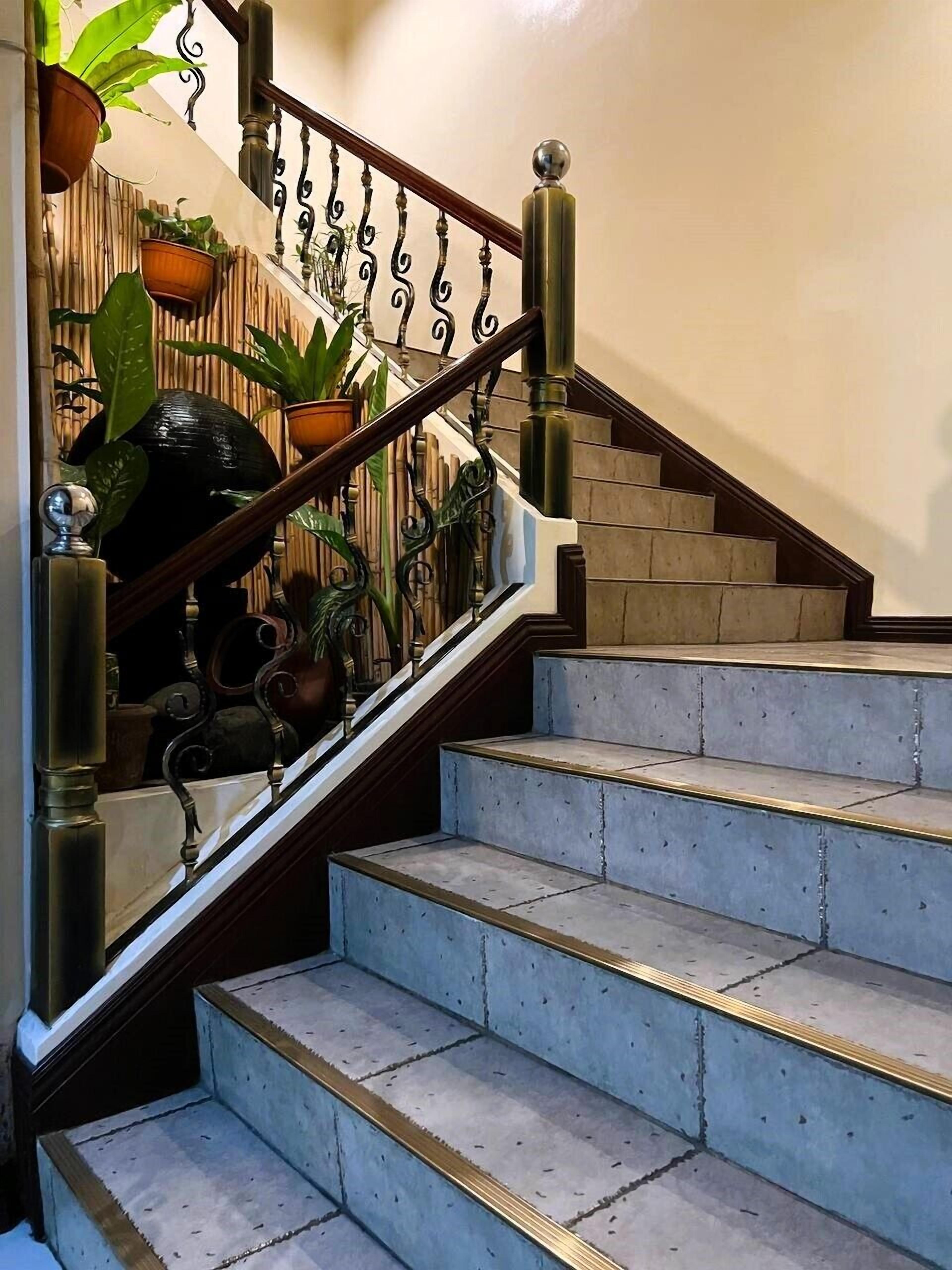 Una escalera con barandilla de madera y balaustradas de metal, que conduce a una plataforma.