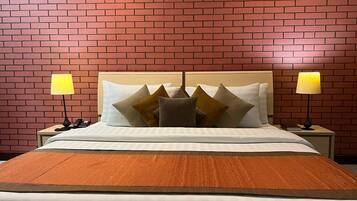 Una cama bien hecha con cabecera de madera, dos lámparas de noche y un pared con diseño de ladrillo.