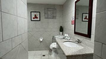 Un baño moderno con un espejo grande, dos lavabos, un inodoro y una ducha.