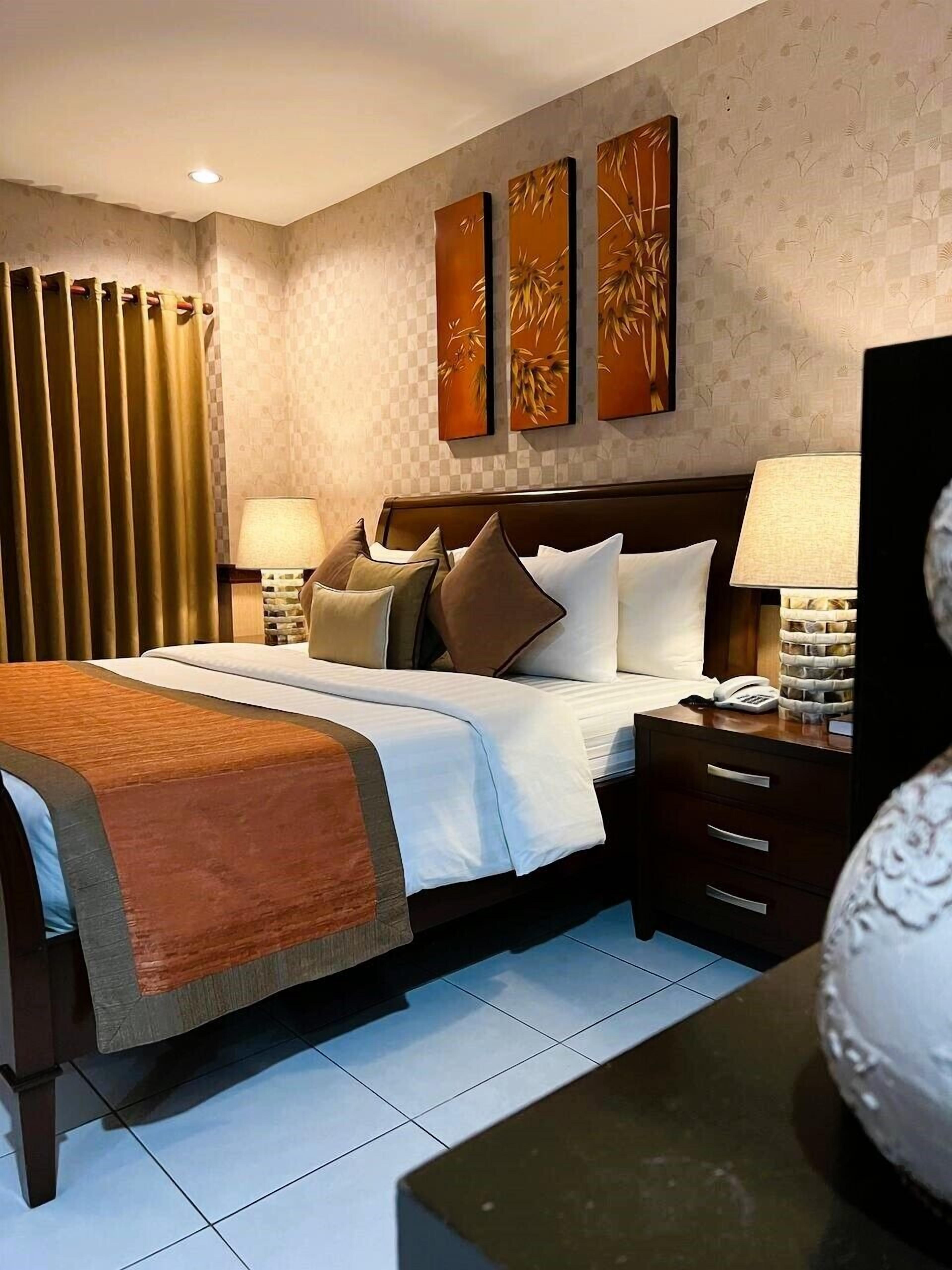 Hotelkamer met een groot bed, twee nachtkastjes, een wandlamp en een kunstwerk aan de muur.