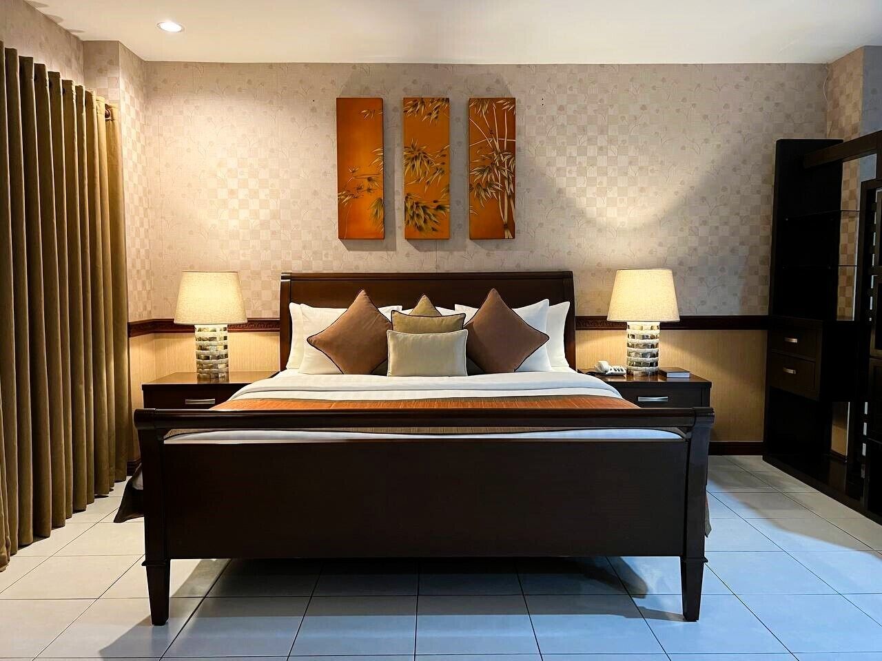 A modern hotel room with a large bed, two bedside tables, and a wall-mounted artwork above the bed.