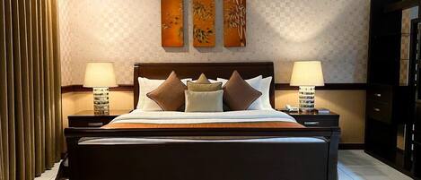 A modern hotel room with a large bed, two bedside tables, and a wall-mounted artwork above the bed.