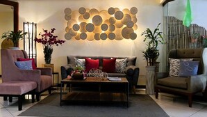 Una sala de estar moderna con sofá, sillones, una mesa de centro y un elemento decorativo en la pared.