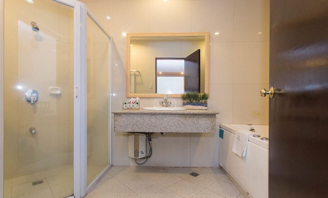 A bathroom with a glass shower enclosure, a sink with a mirror, and a bathtub.
