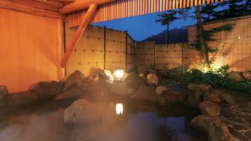 A traditional Japanese onsen with wooden beams and a bamboo fence.