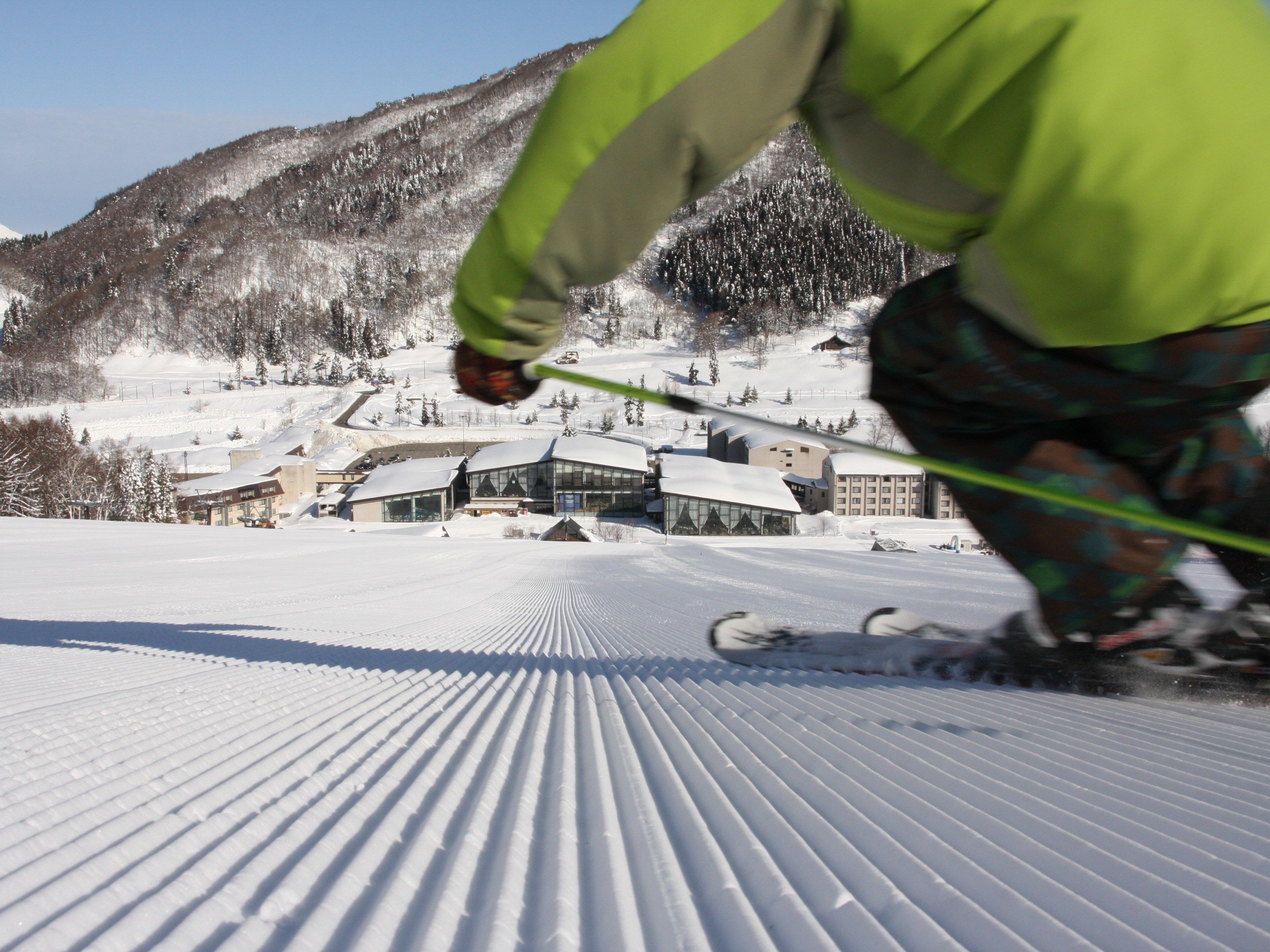 A ski resort with groomed slopes, buildings, and a mountainous backdrop.