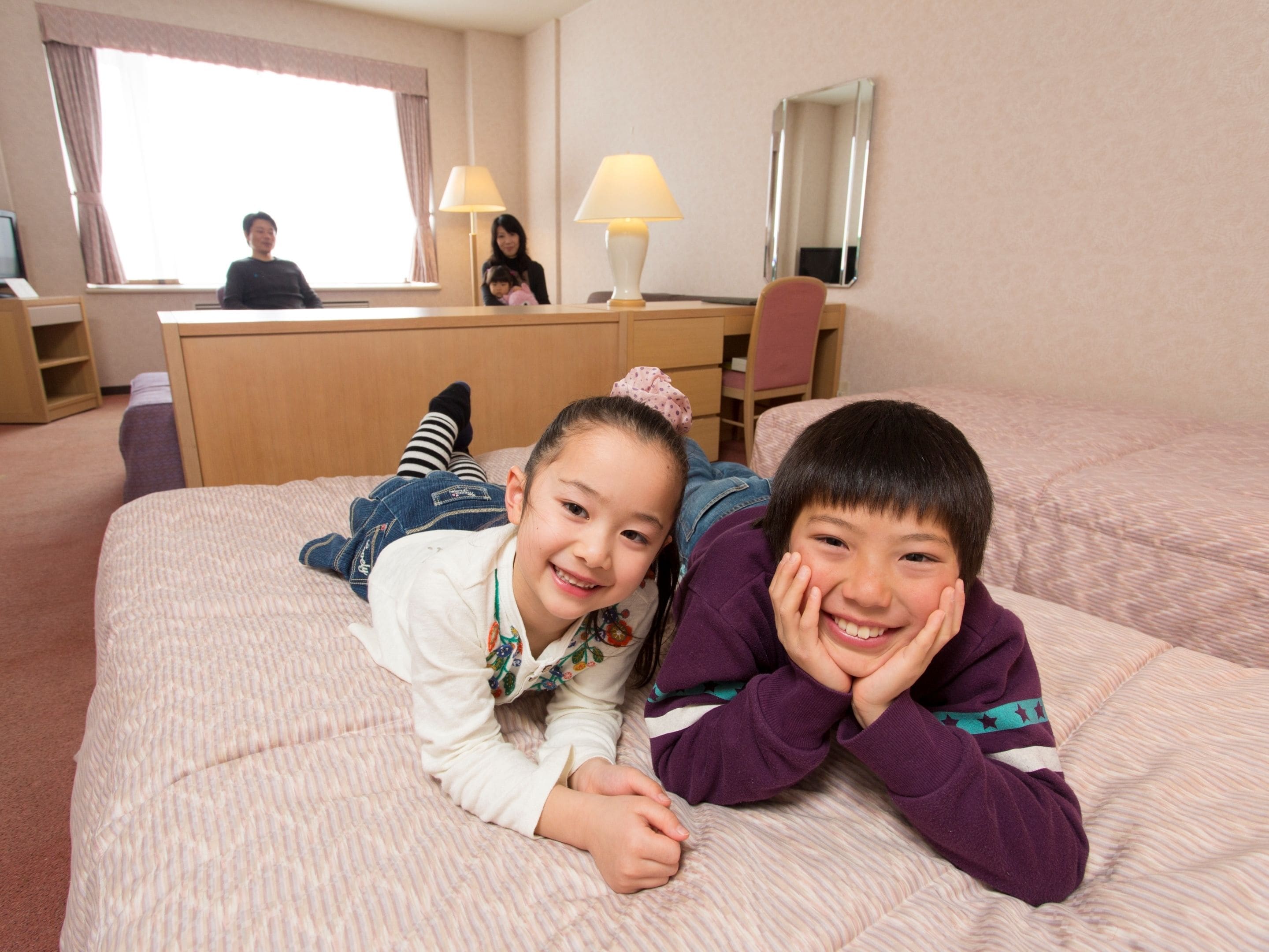 A hotel room with a bed, a desk, a chair, and a window.