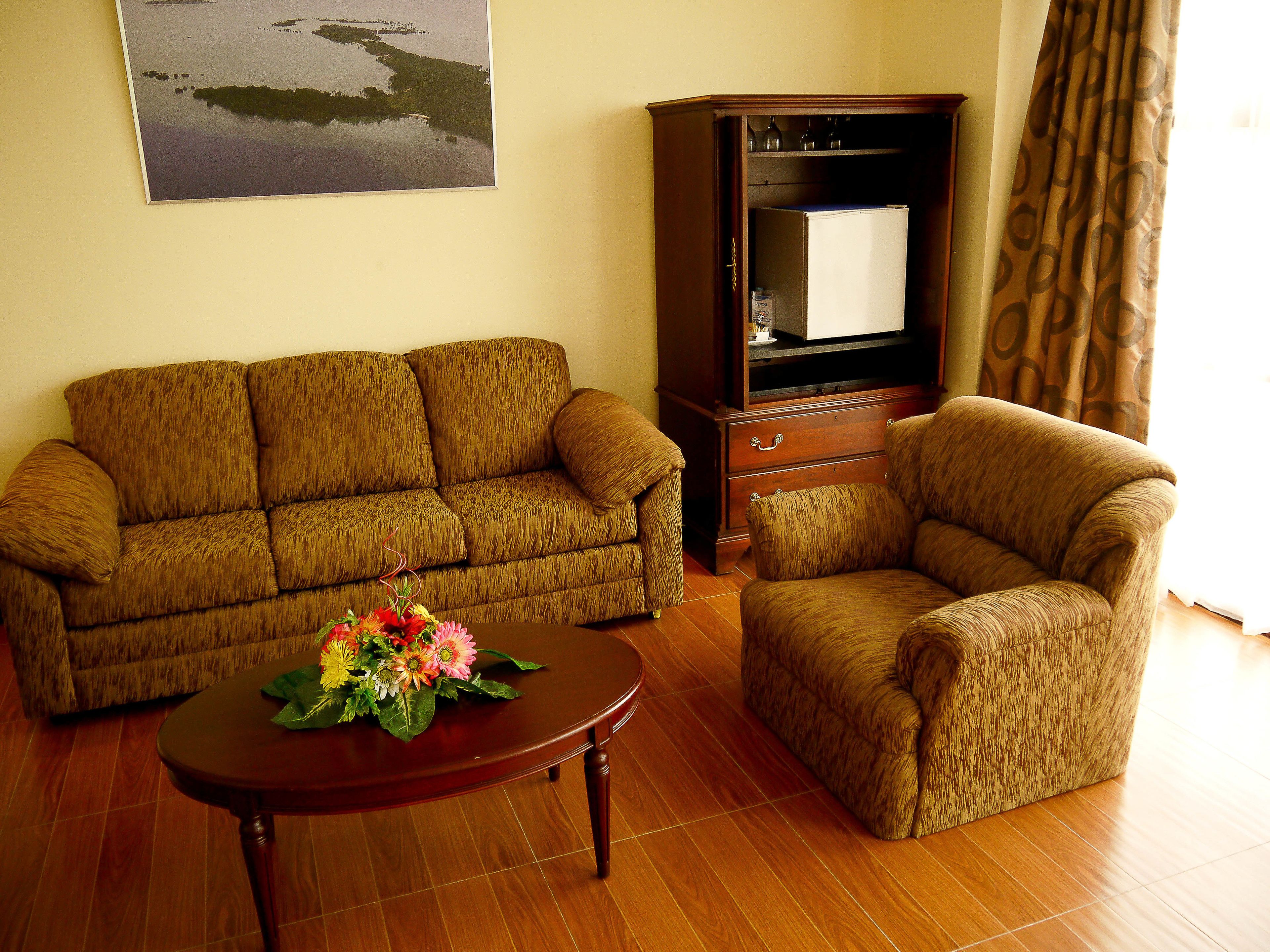 A living room with a sofa, armchair, wooden coffee table, and a cabinet.