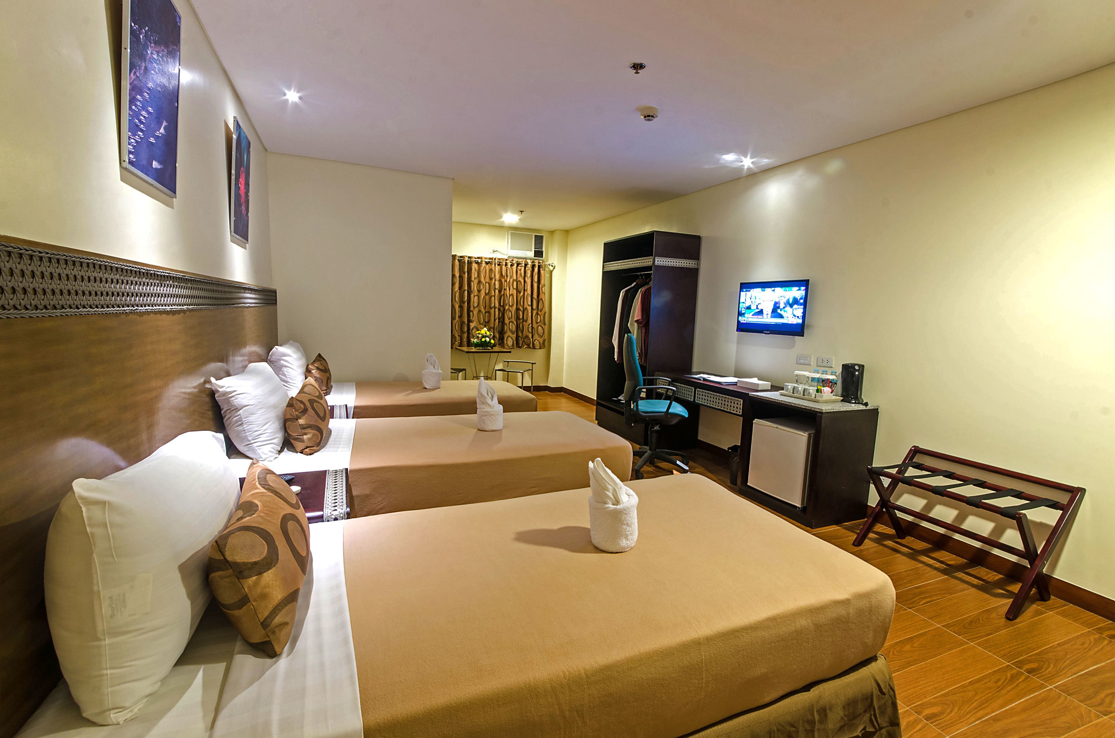 Habitación de hotel con dos camas, un escritorio, una silla, un televisor y una kitchenette pequeña.