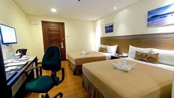 A hotel room with two beds, a desk with a computer, a chair, and a door.