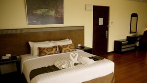 A neatly made bed with towels, a nightstand, a bedside table, a mirror, and a framed picture on the wall. - Fersal Hotel Puerto Princesa (Puerto Princesa)