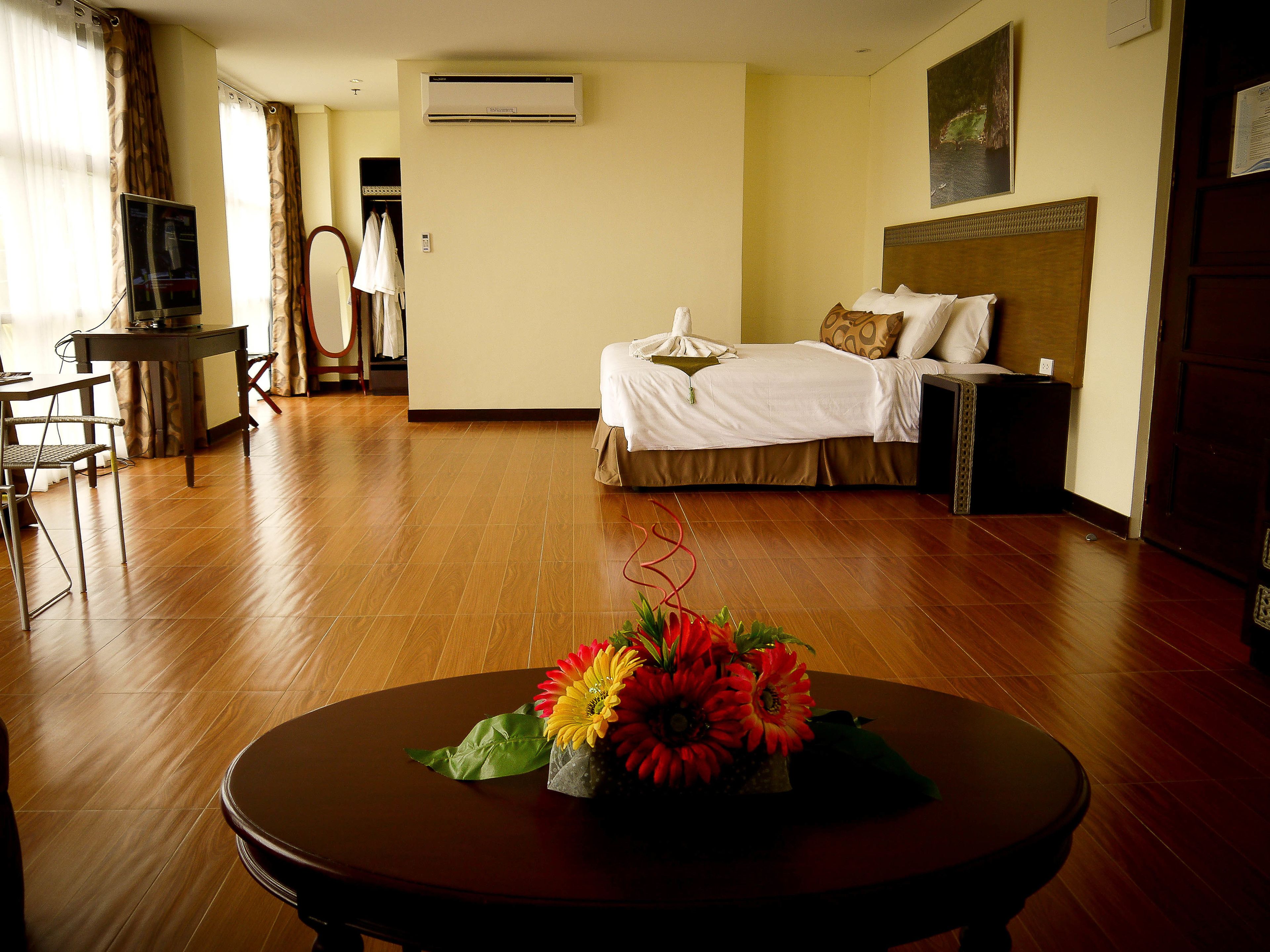 Una habitación de hotel con una cama, un escritorio, una silla y una mesa con flores.